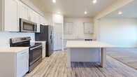 This two-story home offers a thoughtfully designed layout with clean, neutral finishes that create a bright and welcoming atmosphere throughout. The kitchen serves as a functional centerpiece, featuring shaker-style cabinetry in a soft gray tone, a center island with a quartz countertop, stainless steel appliances including a refrigerator with ice maker, electric range, and over-the-range microwave, along with wood-look luxury vinyl plank flooring that adds warmth and durability. Recessed lighting illuminates the space effectively.

The bedrooms are generously sized, each finished with plush carpet and neutral wall tones that lend a calm, comfortable feel. One bedroom is notably spacious and features a ceiling fan, recessed lighting, and multiple windows fitted with white horizontal blinds that allow for excellent natural light control. Bedrooms include well-proportioned closets with paneled doors, while the primary suite is complemented by a walk-in closet outfitted with a custom built-in organization system featuring shelving, hanging space, and built-in drawers.

The bathroom includes a soaking tub with shower combination and a separate water closet, alongside a vanity with quartz countertops and wood-look tile flooring. A dedicated laundry room accommodates a full-size washer and dryer with overhead shelving for added storage.
