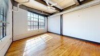 Unit 608 at 101 E. Sixth Street is an urban loft-style residence in downtown Winston-Salem, NC, blending industrial character with modern finishes. Original hardwood floors and exposed steel beams run throughout, while oversized factory-style windows flood the open living area with natural light and offer city views. The kitchen features rich dark cabinetry, granite countertops, stainless steel appliances, and a breakfast bar. Both bedrooms offer hardwood floors and closet space, with the primary bedroom providing direct access to an en-suite bath. The two bathrooms are finished with granite vanities, dark cabinetry, and tile flooring, each equipped with a tub-shower combination.