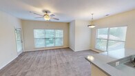 Located at 8310 Carter Creek Dr in Charlotte, NC, this single-floor residence offers a well-designed, functional layout with a warm and inviting ambiance throughout. The open-concept living and dining area is generously proportioned, finished with plush carpeting and bathed in natural light from multiple large windows with blinds. Ceiling fans provide comfort and airflow, while a stylish pendant light adds a decorative accent near the kitchen transition. The kitchen is thoughtfully appointed with white shaker-style cabinetry, a classic subway tile backsplash, a white quartz-style countertop with a breakfast bar overhang, and a full suite of black appliances including a range, microwave, and refrigerator. Hardwood flooring grounds the kitchen space, creating a clean contrast to the carpeted living areas. The bedrooms are comfortably sized with soft carpet, natural light from windows, and ample wall space for flexible furnishing. A dedicated in-unit laundry area houses a full-size washer and dryer with overhead shelving for added storage. The full bathroom features a single-sink vanity with white cabinetry, a tub-shower combination, and hardwood flooring, completing this practical and comfortable home.