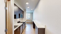 Located on the fourth floor at 252 Broadway in downtown Tacoma, Washington, this efficiently designed studio unit offers a thoughtfully organized layout across a single floor. Light-toned luxury vinyl plank flooring runs throughout, complementing the clean, contemporary aesthetic of the space.

The galley-style kitchen is a standout feature, showcasing dark espresso cabinetry, stone-look countertops, stainless steel appliances including a gas range, built-in microwave, and dishwasher, along with an extended countertop peninsula that provides additional workspace and storage. Recessed lighting overhead and a window at the end of the kitchen bring in natural light.

A sliding barn-style door adds a rustic-modern design element, providing stylish room separation while maximizing the use of the compact footprint. The bathroom is well-appointed with a stone-look vanity countertop, undermount sink, modern fixtures, and dark cabinetry that mirrors the kitchen's design language. A large mirror enhances the sense of space. In-unit laundry adds everyday convenience.

Warm wood door trim accents throughout tie the design together, giving the space a cohesive and polished feel. The unit presents a functional, modern living environment in the heart of Tacoma.