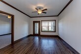 This single-floor residence in Parkville, Missouri, is designed with a contemporary aesthetic, blending functionality and style throughout. The open-concept living and kitchen area serves as the heart of the unit, where rich hardwood-style flooring, bold crown molding, and a ceiling fan create a welcoming atmosphere. Large windows and a glass door flood the living space with natural light while offering views of the surrounding exterior.

The kitchen is well-appointed with dark espresso cabinetry, light quartz countertops, a central island with a built-in sink, and a full suite of stainless steel appliances, including a range, microwave, and refrigerator. Pendant lighting above the island adds a refined touch. A dedicated laundry closet provides in-unit washer and dryer convenience.

The bedrooms feature plush carpeting, ceiling fans, and ample natural light from well-sized windows. One bedroom includes direct access to a full bathroom outfitted with a dark-cabinetry vanity, quartz countertop, undermount sink, and a tub-shower combination set against wood-look flooring. Consistent dark trim, neutral walls, and quality finishes unify the space throughout.