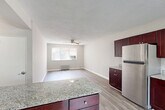 Located at 16 Crescent Rd in Greenbelt, Maryland, this one-bedroom, one-bathroom residence offers a well-organized single-floor layout with a practical and comfortable flow throughout. Light-toned hardwood-style flooring runs continuously through all living areas, lending a clean, cohesive look to the space.

The kitchen is a standout feature, boasting rich dark mahogany cabinetry, granite countertops, a tile backsplash, and an L-shaped peninsula that opens toward the living and dining areas. A black electric range, stainless steel refrigerator, and sink complete the functional setup. The open-concept design allows the kitchen to flow naturally into the dining and living areas, where a ceiling fan, a window with vertical blinds, and a radiator provide comfort and natural light.

The bedroom is a generously proportioned retreat with neutral gray walls, a ceiling fan, a radiator, and a window that brings in natural light. Two closets provide ample storage throughout the unit. The full bathroom features a clean white tub/shower combination with chrome fixtures and a window for ventilation. A textured ceiling is consistent throughout the unit, adding subtle visual character. The entrance provides a welcoming transition into the home's efficiently designed interior.