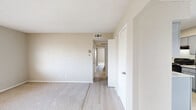 This single-story home features 4 bedrooms, 2 full bathrooms, and 3 closets, all arranged within a practical and well-organized floor plan. Throughout the home, a neutral color palette of warm beige and soft white tones creates a clean, cohesive aesthetic. Textured ceilings are present throughout, adding a subtle dimensional quality to each room.

The bedrooms are carpeted for comfort, with the spacious primary bedroom featuring light wood-style flooring in the connecting hallway and closet access. Several bedrooms include ceiling fans with light fixtures and windows fitted with blinds, allowing for natural light and ventilation control. The bedrooms offer versatile layouts suitable for a variety of furniture configurations.

The galley-style kitchen is outfitted with grey cabinetry, granite-style countertops, a double stainless steel sink, and stainless steel appliances including a refrigerator and range. Light wood-style flooring runs through the kitchen and connects to an adjacent dining or living area, enhancing the sense of continuity.

Both bathrooms are finished consistently with grey vanity cabinetry, granite-style countertops, white vessel sinks, and tub-shower combinations. Light tile flooring and windows providing natural light give the bathrooms a bright, functional feel. The overall design of this home prioritizes practicality and clean finishes throughout.