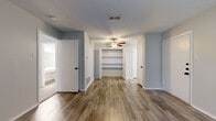 This efficiently designed 2-bedroom, 1-bathroom single-floor unit offers a practical and well-appointed layout throughout. The living areas feature durable wood-look plank flooring in warm neutral tones, complemented by textured ceilings and ceiling fans that appear in multiple rooms for added comfort and airflow.

The galley-style kitchen is a standout feature, outfitted with crisp white cabinetry, light countertops, a stainless steel sink, and a full suite of stainless steel appliances including a refrigerator, range, microwave, and dishwasher — providing a clean, modern aesthetic in a space-efficient layout.

The spacious primary bedroom is a generous retreat, complete with wood-look flooring, a ceiling fan, and access to built-in open shelving within a dedicated closet space. The second bedroom features plush carpeting, a ceiling fan, and a window that allows natural light to fill the room. A walk-in closet with shelving is accessible from the primary area, adding valuable storage.

The full bathroom is cleanly finished with a single-sink vanity featuring white cabinetry and light countertops, a tub-shower combination with tile surround, and wood-look flooring that ties the space together. The neutral gray walls throughout the unit create a cohesive, move-in-ready atmosphere.