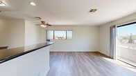 Located on Burbank Boulevard in the Van Nuys neighborhood of Los Angeles, this 2-bedroom, 2-bathroom unit is laid out on a single floor, offering a functional and comfortable living arrangement. The open living area is bright and airy, featuring light wood-style flooring, a ceiling fan with integrated lighting, and a wide window that frames neighborhood views and brings in generous natural light. A raised kitchen counter seamlessly divides the kitchen from the living space, maintaining an open feel while defining each area. The galley-style kitchen is well-equipped with warm wood cabinetry, dark countertops, stainless steel appliances including a gas range, dishwasher, refrigerator, and built-in microwave. The primary bedroom is a comfortable size, enhanced by large sliding glass doors that open onto a private balcony with open views of the surrounding neighborhood. The second bedroom features its own window with neighborhood views and a mirrored sliding closet. A hallway connects the bedrooms to the rest of the unit, with closet storage visible along the corridor. The bathrooms feature wood-toned vanities with dark countertops. Light wood-style flooring runs consistently throughout, tying the space together with a clean, cohesive aesthetic.