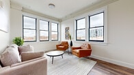 Located at 174 E Long St in the heart of Columbus, OH, this one-bedroom, one-bathroom unit offers an efficient and thoughtfully designed layout. Hardwood-style flooring runs throughout, providing a cohesive and modern aesthetic across every room.

The galley kitchen is lined with crisp white cabinetry and equipped with stainless steel appliances, including a full-size refrigerator, microwave, and range. Recessed lighting and an exposed overhead duct add an industrial touch to the clean, minimal design. A hallway connects the kitchen to the rest of the unit, with decorative wall accents adding a warm, personal touch.

The living area is a standout feature, wrapped on two sides by large black-framed windows that flood the space with natural light and frame sweeping views of the Columbus skyline and surrounding cityscape. Ornamental crown molding details along the upper walls hint at the building's historic character.

The bedroom continues the bright, airy feel with its own set of black-framed windows overlooking the city, paired with the same hardwood-style flooring for a consistent finish. The bathroom features a tub-shower combination with a curtain enclosure, a gray vanity with under-sink storage, and wood-look flooring that ties seamlessly into the rest of the unit.