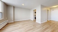 This 2-bedroom, 2-bathroom residence is thoughtfully designed to maximize functionality and comfort across a single floor. Light-toned hardwood flooring flows consistently throughout the space, creating a cohesive and contemporary aesthetic.

The open living room is bright and welcoming, anchored by a large floor-to-ceiling window that frames sweeping city views and floods the room with natural light. A baseboard heating system runs along the window wall, and a textured ceiling adds subtle character to the space.

Adjacent to the living area, the kitchen features clean white cabinetry with ample storage, white countertops, a subway tile backsplash, and stainless steel appliances including a range, over-the-range microwave, and dishwasher. The efficient layout makes excellent use of the available space.

The primary bedroom is generously sized, offering a large window with city views and a sliding panel closet. The second bedroom is well-proportioned and includes a separate closet with convenient hallway access. Both rooms continue the light hardwood flooring and neutral wall tones.

The two bathrooms each feature a full soaker tub and shower combination. One is finished with crisp white subway tile, while the other features warm grey linear tile, offering a distinct character in each. The overall design is clean, modern, and move-in ready.