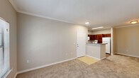 Located at 6795 Belle Vale Dr in Addis, Louisiana, this single-story, one-bedroom, one-bathroom home offers a thoughtfully designed layout across a comfortable footprint. The open living area features neutral-toned carpet, crown molding, and ceiling-mounted HVAC vents, creating a clean and cohesive aesthetic. Natural light filters in through window blinds, enhancing the bright, airy feel of the space.

The kitchen is a functional highlight, featuring rich dark wood cabinetry, granite-style countertops, hardwood-style flooring, and a full suite of white appliances including a refrigerator, electric range, built-in microwave, and dishwasher. A breakfast bar connects the kitchen to the living area, offering a convenient casual dining option.

The bedroom is generously sized with plush carpet, a ceiling light fixture, and a large window that brings in natural light. It includes a built-in desk or shelf nook and access to a spacious walk-in closet outfitted with wire shelving and hanging rods for ample storage.

The bathroom offers a clean, classic design with dark wood cabinetry, a single vanity with a light-toned countertop, a large mirror with an overhead light bar, and hardwood-style flooring. A hallway connects all rooms, completing this well-organized and efficiently planned home.