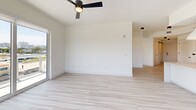 Located at 2335 NE 186th St, Unit 313 in Miami, FL, this thoughtfully designed 3-bedroom, 2-bathroom residence offers a bright, contemporary living experience. The open-concept kitchen and living area serves as the heart of the home, featuring flat-panel white cabinetry extending to the ceiling, stainless steel appliances, a wine refrigerator, and a large center island with a built-in sink illuminated by stylish pendant lighting. Light wood-tone flooring flows seamlessly throughout, enhancing the clean, modern aesthetic. The spacious living room is bathed in natural light through floor-to-ceiling sliding glass doors that open onto a private balcony with glass-railed views of Miami's lush tropical canopy and city skyline. A ceiling fan completes the airy feel of the main living space. The generously sized primary bedroom features its own access to outdoor views and is complemented by a well-organized walk-in closet with custom built-in shelving and dual hanging sections. Two additional bedrooms offer ample space, ceiling fans, and abundant natural light. Both bathrooms are finished with clean white tile and contemporary matte black fixtures. Two closets provide excellent storage throughout. The unit's crisp white walls, minimalist design, and abundance of natural light create a bright, welcoming atmosphere throughout.