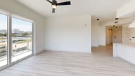 Located at 2335 NE 186th St, Unit 313 in Miami, FL, this thoughtfully designed 3-bedroom, 2-bathroom residence offers a bright, contemporary living experience. The open-concept kitchen and living area serves as the heart of the home, featuring flat-panel white cabinetry extending to the ceiling, stainless steel appliances, a wine refrigerator, and a large center island with a built-in sink illuminated by stylish pendant lighting. Light wood-tone flooring flows seamlessly throughout, enhancing the clean, modern aesthetic. The spacious living room is bathed in natural light through floor-to-ceiling sliding glass doors that open onto a private balcony with glass-railed views of Miami's lush tropical canopy and city skyline. A ceiling fan completes the airy feel of the main living space. The generously sized primary bedroom features its own access to outdoor views and is complemented by a well-organized walk-in closet with custom built-in shelving and dual hanging sections. Two additional bedrooms offer ample space, ceiling fans, and abundant natural light. Both bathrooms are finished with clean white tile and contemporary matte black fixtures. Two closets provide excellent storage throughout. The unit's crisp white walls, minimalist design, and abundance of natural light create a bright, welcoming atmosphere throughout.