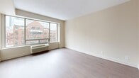 Located at 210 Somerset St W in Ottawa's Centretown neighbourhood, this one-bedroom, one-bathroom unit offers a well-organized single-floor layout designed to maximize every square foot. The main living area is bright and open, featuring light-toned hardwood-style flooring and a large picture window that draws in generous natural light while offering views of the surrounding urban streetscape. Neutral warm beige walls and clean white trim give the space a simple, cohesive aesthetic throughout.

The kitchen is neatly appointed with white shaker-style cabinetry, clean white countertops, a stainless steel sink, and ample upper and lower cabinet storage — ideal for efficient everyday use. The bedroom is the most spacious room in the unit, accommodating comfortable furnishing arrangements, and is accessed via a short hallway that also connects to a dedicated closet and the bathroom.

The bathroom features a white vanity with under-cabinet storage, a mirrored medicine cabinet, and tile flooring, maintaining the clean and functional design language found throughout the unit. A built-in HVAC unit beneath the main window ensures year-round climate control. Overall, this unit offers a practical and tidy living environment in a well-connected Ottawa location.