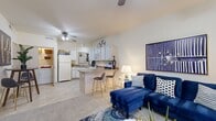 This thoughtfully designed one-bedroom, one-bathroom residence features an efficient single-floor layout that maximizes every inch of living space. The open-concept kitchen and living area serves as the heart of the home, where the kitchen flows seamlessly into the living room via a peninsula breakfast bar with seating for two — ideal for casual dining or entertaining. The kitchen is equipped with white cabinetry, a full suite of white appliances including a refrigerator, dishwasher, electric range, and built-in microwave, along with a double sink and tile flooring. Vaulted ceilings and ceiling fans enhance the sense of openness in the living area, which features soft carpet, large windows that invite natural light, and a welcoming entryway nook with additional window views. The bedroom is a well-proportioned retreat with plush carpet, a ceiling fan, and a generously sized window that brings in natural light. It also features access to a walk-in closet. The full bathroom is finished with tile flooring, a wide vanity with ample cabinet storage, a medicine cabinet, and a shower-tub combination with sliding glass doors. Throughout the residence, neutral wall tones create a clean, versatile backdrop.