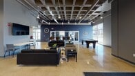 Located at 2827 Rupp Dr in Fort Wayne, Indiana, this single-story community facility presents a thoughtfully designed, open-concept interior that balances functionality with modern aesthetics. The space is defined by its polished terrazzo flooring, which flows seamlessly throughout, and a striking exposed ceiling system featuring a grid-patterned cofferwork with visible ductwork and industrial-style pendant lighting that adds architectural character.

The welcoming entrance lobby greets visitors with a bold "welcome" wall treatment, a central round accent table, and sleek dark column cladding, setting an inviting tone. Large floor-to-ceiling windows line the perimeter, flooding the interior with natural light and offering views of the surrounding landscape.

The expansive main lounge area is anchored by deep navy blue accent walls and furnished with multiple seating arrangements, including leather sofas and lounge chairs positioned around coffee tables atop geometric-patterned area rugs. Game amenities are prominently featured, with both a billiards table and a ping-pong table providing recreational options. A wall-mounted flat-screen television and a dedicated seating nook with high-top tables further enhance the space's versatility.

An entry vestibule with glass-panel doors and an information display wall provides a functional transition point. Throughout, the combination of contemporary finishes, open sightlines, and recreational offerings makes this a well-appointed, multi-use community gathering space.