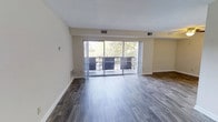 This single-floor residence offers a well-designed layout suited for comfortable everyday living. The open living area is a standout feature, showcasing wide-plank hardwood-style flooring that adds a modern, polished aesthetic throughout the space. Neutral-toned walls provide a clean, versatile backdrop that complements a variety of décor styles.

A large sliding glass door serves as the focal point of the main living area, flooding the space with abundant natural light and offering direct access to a private balcony. The balcony is framed by lush, mature trees, creating a serene and natural outdoor retreat. The seamless transition between the interior and exterior enhances the sense of openness and scale within the living space.

Ceiling-mounted HVAC vents are integrated throughout, ensuring year-round climate comfort. The layout flows thoughtfully across the single floor, connecting the living area to the rest of the home with ease. With its combination of contemporary finishes, generous natural light, and a tranquil outdoor connection, this residence provides a welcoming and functional living environment well-suited for a range of lifestyles.