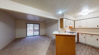 Located at 3437 Bay Pointe Dr in Elkhart, Indiana, this single-floor residence features a practical, open-concept layout connecting the kitchen and living areas. The kitchen is equipped with white cabinetry accented by wood-tone hardware, a gas range, a dishwasher, a built-in range hood, and ample counter space. Wood-look vinyl flooring adds a clean, durable finish to the cooking area. A peninsula with warm oak cabinetry visually separates the kitchen from the adjacent living space, which features neutral carpet and a sliding glass door that allows natural light and provides outdoor views. The living area is generously proportioned, offering flexible arrangement possibilities. A second carpeted room, also accessed by sliding glass doors, serves well as a bedroom or additional living space. The walk-in closet is outfitted with multi-tier wire shelving, providing well-organized storage capacity. The bathroom features a soaking tub with a tiled surround, wood-look vinyl flooring, and a skylight that introduces natural light overhead. Louvered closet doors are a consistent design element throughout the home. The overall aesthetic is clean and neutral, presenting a move-in ready space with functional features suited for comfortable everyday living.