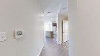 This 1,250 sq ft apartment at One Upland in Norwood, MA features 4 bedrooms, 3 bathrooms, and a well-designed single-floor layout. The open-concept kitchen and living area is a standout, showcasing rich dark-brown cabinetry, stainless steel appliances, a gas range, and a white quartz island, all complemented by light wood-style flooring. Recessed lighting illuminates the space throughout. The living area benefits from large windows that invite natural light and includes access to an outdoor area via sliding glass doors dressed with vertical blinds. Bedrooms are generously sized, featuring plush carpeting, ample natural light from multiple windows, and neutral tones. The 180 sq ft primary bedroom includes a walk-in closet with built-in wire shelving. Bathrooms are finished with large-format tile flooring, dark wood vanities with white countertops, and clean white-tiled walk-in showers. One bathroom also features a dedicated linen closet. A separate closet adds additional storage. The unit's modern aesthetic is consistent throughout, combining functional design with contemporary materials for a polished, move-in-ready living experience.