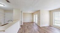 Located at 6300 Moseley Dixon Rd in Macon, Georgia, this efficient one-bedroom, one-bathroom unit offers a practical and comfortable single-floor layout. Wood-look flooring runs throughout the space, lending a warm, cohesive aesthetic from room to room.

The open living area flows directly into the kitchen, which is outfitted with white cabinetry, light countertops, and black appliances including a refrigerator, electric range, and over-the-range microwave — providing a functional cooking environment. A peninsula-style counter separates the kitchen from the living space, creating a natural division while maintaining an open feel.

The living room features neutral walls and ample wall space, allowing for flexible furniture arrangements. Natural light enters through multiple windows fitted with blinds, brightening the interior throughout the day.

The bedroom is a comfortable size, featuring a ceiling fan with a built-in light fixture, a window with outdoor views, and access to a dedicated walk-in closet complete with built-in shelving and hanging rods — offering excellent storage capacity.

The bathroom includes a full tub and shower combination with chrome fixtures, complemented by wood-look flooring consistent with the rest of the unit. Clean, neutral finishes throughout the space create a move-in ready environment suited for straightforward, comfortable living.