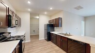 Located at 801 Booth Rd in Warner Robins, Georgia, this single-floor, three-bedroom, two-bathroom home offers a well-designed layout with a cohesive, modern aesthetic throughout. The galley-style kitchen is a standout feature, showcasing rich dark-wood cabinetry, white countertops, black appliances including a refrigerator, range, microwave, and dishwasher, and a double-basin sink — all set atop durable wood-look plank flooring. An adjacent utility/laundry area adds everyday convenience. The living room is bright and inviting, highlighted by French doors that allow natural light to pour in and provide access to an outdoor area. Bedrooms are finished with plush carpeting, and the primary bedroom includes a ceiling fan, dual windows with exterior views, and a dedicated walk-in closet with wraparound shelving. The secondary bedrooms also feature soft carpet and neutral tones, offering versatile living spaces. The bathrooms are clean and functional, with wood-look flooring, a soaking tub with grab bar, and understated finishes. Warm neutral wall tones and recessed lighting carry throughout the home, creating a consistent and comfortable ambiance well-suited for everyday living.