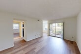 Located at 940 Quaker Ln in Warwick, Rhode Island, this single-floor, one-bedroom, one-bathroom unit offers a practical and comfortable layout. Throughout the space, light wood-style flooring provides a clean, cohesive look, complemented by neutral white walls and textured ceilings that add subtle character.

The unit features two connected living areas, offering flexible space for both lounging and dining arrangements. Natural light flows in through multiple windows, with views of the surrounding greenery creating a pleasant outdoor connection. The entry area opens into a bright, open main living room.

The galley-style kitchen is well-appointed with warm wood cabinetry, granite-look countertops, a double stainless steel sink, and a full suite of black appliances including a refrigerator, range, microwave, and dishwasher. A window at the end of the kitchen frames a scenic outdoor view, making the space feel open and airy.

The generously sized primary bedroom features a large window overlooking mature trees, providing both natural light and privacy. A dedicated closet adds convenient storage.

The bathroom includes a full tub and shower combination with white tile surround, grab bars for accessibility, and a wood-toned storage cabinet. The overall design is clean, functional, and move-in ready.