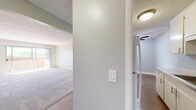 Located at 13495 Bancroft Ave in San Leandro, CA, this one-bedroom, two-bathroom residence offers a practical and comfortable single-floor layout. The open living room is spacious and bright, featuring soft carpet flooring, a sliding glass door that leads to a private balcony with outdoor views, and a wall-mounted mini-split unit for climate control. Natural light flows generously throughout this area, creating a welcoming atmosphere.

The galley-style kitchen runs parallel along one wall, outfitted with white cabinetry offering ample upper and lower storage, a stainless steel sink, a black electric range, and a refrigerator. Wood-look flooring runs through the kitchen, complementing the clean, neutral palette found throughout the home.

The primary bedroom is a well-proportioned retreat featuring plush carpeting, a wide window with treetop views that fill the room with natural light, and a dedicated closet with built-in shelving. A second versatile room with a ceiling fan and textured flooring adds flexible space to the layout.

Both bathrooms are clean and functional; one features a full soaking tub with white tile surround, while the other includes a vanity with white cabinetry and a mirror. A hallway connecting the bedroom area to the living space features wood-look flooring and access to the closet storage. The consistent light gray walls and neutral finishes throughout create a cohesive, move-in-ready environment.