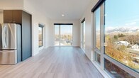 Located at 311 N Willson Ave in Bozeman, MT, this modern 2-bedroom, 2-bathroom residence offers a thoughtfully designed single-level layout with clean architectural lines and high-end finishes throughout. The open living area is a standout, wrapped in expansive floor-to-ceiling windows that flood the space with natural light and frame breathtaking panoramic views of the surrounding Bozeman mountains and cityscape. Light-toned hardwood flooring runs seamlessly throughout, complementing the crisp white walls and recessed lighting.

The kitchen features a contemporary two-tone design with dark navy lower cabinets, light wood upper cabinetry, sleek countertops, a glass backsplash, and stainless steel appliances including a range and dishwasher. Both bedrooms are bright and well-proportioned, with large picture windows offering elevated views of the mountains and neighborhood. The primary bedroom provides a comfortable, private retreat. Each of the two bathrooms is finished in a modern style, showcasing dark-toned floating vanities with open shelving, under-lit LED-framed mirrors, and chrome fixtures. The primary bath includes a frameless sliding glass walk-in shower. A clean, well-lit hallway with recessed lighting connects the rooms efficiently, completing this polished and contemporary residence.