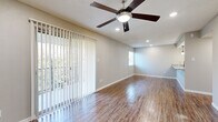 Located in Austin's sought-after 78704 zip code, this single-story home offers four bedrooms and two full bathrooms across a well-organized floor plan. The living area is bright and open, showcasing rich wood-look flooring that runs throughout the main spaces, a ceiling fan with integrated lighting, and recessed lights that add warmth to the room. Large vertical-blind-covered sliding doors and windows invite abundant natural light while framing views of the surrounding greenery. The layout connects the living area to the kitchen, which is equipped with stainless steel appliances, a dishwasher, and granite-look countertops, providing a functional and modern workspace. Both bathrooms feature a clean, classic aesthetic with large-format white subway tile surrounding deep soaking tub-shower combos, brushed nickel fixtures, and wood-look flooring—complemented by white cabinetry with black hardware and granite countertops. The bedrooms are carpeted for comfort and each includes a ceiling fan, offering a quiet retreat. Neutral gray tones throughout the home create a cohesive, move-in-ready atmosphere suited for a variety of living arrangements.