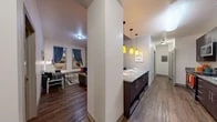 Located at 5 Court St in Binghamton, NY, this 2-bedroom, 2-bathroom unit offers a well-planned, single-floor layout that makes efficient use of its space. Rich hardwood-style flooring runs throughout the main living areas, lending warmth and continuity to the open feel.

The galley-style kitchen is a standout feature, outfitted with dark espresso cabinetry, granite countertops, and a full suite of stainless steel appliances including a refrigerator, range, microwave, and dishwasher. A peninsula counter with pendant lighting in vibrant yellow tones serves as a natural divider between the kitchen and living area, doubling as a dining space.

The living room is bright and welcoming, with windows dressed in blue curtains that allow natural light to fill the room. Its neutral walls and hardwood-style flooring create a versatile backdrop for any décor style.

Both bedrooms are carpeted for comfort and feature windows with outdoor views, open closet areas, and ample room for furnishings. The spacious primary bedroom provides a quiet, functional retreat.

The two bathrooms are clean and practical, featuring dark vanity cabinetry, stone-patterned tile flooring, and well-lit mirrors. A dedicated closet rounds out the storage options within this thoughtfully designed unit.