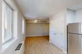 Located at 7400 Parkwood Ct, Unit 101 in Falls Church, Virginia, this efficiently designed single-floor unit offers a thoughtfully organized living space with a clean, modern aesthetic. The open-concept layout maximizes the available footprint, seamlessly connecting the kitchen and living area for a functional and cohesive feel.

The kitchen is well-appointed with warm honey-toned wood cabinetry, granite-look countertops, and a full suite of stainless steel appliances, including a gas range, over-the-range microwave, refrigerator, and dishwasher. A skylight overhead fills the kitchen with natural light, enhancing the bright and airy atmosphere. The layout features a partial dividing column that subtly defines the kitchen from the open living area without sacrificing the sense of space.

The living area is finished with light wood-style flooring that runs throughout the unit, contributing to a warm yet contemporary look. Soft gray walls and white trim create a neutral, versatile backdrop. A ceiling fan with an integrated light fixture provides comfort and illumination, while windows overlooking greenery allow natural light to filter in.

Additional features include an entryway with a utility panel, an interior door leading to a bathroom or closet area, and a layout designed to make every square foot count. The overall ambiance is clean, bright, and move-in ready.