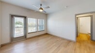 Located in Knoxville, TN, this well-appointed single-floor residence offers three bedrooms and two bathrooms with a clean, contemporary aesthetic throughout. The kitchen is a standout feature, showcasing a two-tone cabinet design with crisp white uppers and slate-gray lowers, a subway tile backsplash, stainless steel appliances including a French door refrigerator, electric range, built-in microwave, and dishwasher. A large center island with a quartz countertop provides additional workspace and serves as a natural gathering point. Warm light wood flooring flows through the kitchen and living areas, while recessed lighting and pendant fixtures provide bright, even illumination. The living area offers access to a private balcony through glass-panel doors, with a ceiling fan and windows that invite natural light and outdoor views. The bedrooms are finished with plush carpet and neutral walls, offering versatile, comfortable spaces. The primary bedroom includes a generous walk-in closet outfitted with wire shelving for efficient storage. The primary bathroom features a glass-enclosed shower and tub combo, a gray vanity with quartz countertop, and light wood flooring. The secondary bathroom mirrors the same refined, modern finishes. A hallway connects the layout cohesively, completing this thoughtfully designed residence.