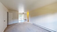 Located on Stratford Lane in Middletown, NY, this single-floor unit offers a practical and comfortable layout across several well-appointed rooms. The living area is spacious and carpeted, featuring a ceiling fan, baseboard heating, and a sliding glass door that allows natural light to pour in while providing outdoor views — creating a bright and welcoming atmosphere. An adjacent carpeted room offers additional versatile living space, also equipped with baseboard heating and a wall-mounted air conditioning unit, along with a window overlooking greenery outside.

The kitchen stands out with its modern finishes, including crisp white cabinetry, dark granite-style countertops, a mosaic tile backsplash, and a full suite of stainless steel appliances — including a range, dishwasher, and range hood. The hardwood-style flooring in the kitchen adds a clean contrast to the carpeted rooms throughout the rest of the unit.

The bedrooms are calm and neutral, with plush carpeting, baseboard heating, and ample natural light. A closet is accessible in one of the bedrooms, providing convenient storage. The full bathroom is neatly finished with tile flooring, a white vanity, a tub-shower combination, and a window that keeps the space bright and well-ventilated.