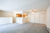 Located at 215 Spruce Dr in Holbrook, NY, this single-floor residence offers a straightforward and functional layout throughout. The living area is generously proportioned, featuring neutral wall-to-wall carpeting, baseboard heating, and a sliding glass door that opens onto an outdoor deck, allowing natural light to fill the space and providing views of the surrounding greenery. A pass-through window connects the living area to the kitchen, creating an open sightline between the two spaces.

The kitchen is equipped with warm-toned wood cabinetry offering ample upper and lower storage, light-colored countertops, and tile flooring. Appliances include a range with an over-the-range microwave, a dishwasher, and a full-size refrigerator, providing a complete and practical cooking environment.

The bedrooms are carpeted and feature ceiling light fixtures, windows with natural light, and sliding closet doors with built-in hanging rods for storage. The bathroom includes a vanity with a single sink, a wide mirror cabinet, and a shower with sliding glass doors, finished in a clean, neutral palette.

A dedicated in-unit laundry area with a washer is accessible from the main living space, adding convenience. Overall, the residence presents a practical and livable environment in a quiet Long Island community.