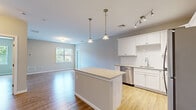 Located at 731 Federal Rd in Brookfield, CT, this two-bedroom, one-bathroom residence offers a well-designed single-floor layout with modern finishes throughout. The open-concept kitchen is a standout feature, boasting white shaker cabinetry, white subway tile backsplash, granite countertops, and a full suite of stainless steel appliances including a gas range, built-in microwave, dishwasher, and refrigerator. A central kitchen island with a granite top provides additional prep and seating space, while dual pendant lights and a track lighting system add functional style. The kitchen flows seamlessly into the living area, which is bright and airy, featuring light hardwood-style flooring and neutral gray walls that create a clean, versatile canvas. Both bedrooms are generously sized with large windows that invite abundant natural light and offer views of the surrounding greenery. The primary bedroom provides ample space and is complemented by a dedicated closet. The bathroom is well-appointed with a full tub-shower combo, a dark espresso vanity with a white countertop, a large mirror, and light tile flooring. Hardwood-style flooring runs consistently throughout the living spaces, tying the home together with a cohesive, contemporary aesthetic.