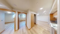Located at 1801 E Yesler Way in Seattle's vibrant Capitol Hill neighborhood, this three-bedroom, one-bathroom unit offers a thoughtfully designed single-floor layout. Light hardwood flooring runs throughout, complementing the clean, neutral-toned walls and warm wood trim that give the space a cohesive, modern aesthetic.

The open kitchen and living area form the heart of the unit. The kitchen is equipped with warm wood cabinetry, gray stone-finish countertops, a double-basin sink, white appliances including a refrigerator and dishwasher, and recessed lighting overhead. It flows naturally into the spacious living area, which receives ample natural light through a large floor-to-ceiling window offering views of the surrounding Seattle cityscape.

The three bedrooms each feature hardwood flooring and access to natural light. The primary bedroom is generously sized and includes a closet with built-in shelving. Additional bedrooms offer closet space and windows with neighborhood views. A shared hallway connects the sleeping quarters efficiently.

The bathroom is clean and functional, featuring a full soaking tub with shower, grab bars, a wood-cabinet vanity with stone countertop, and a large mirror. The overall design is modern and practical, making this unit a well-appointed home in one of Seattle's most walkable and connected neighborhoods.