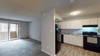 Located at 8 Covey On in Greensboro, NC, this single-floor unit offers a practical and well-organized layout designed for comfortable everyday living. The living area is generously sized, featuring soft wall-to-wall carpeting in a neutral gray tone and a textured ceiling throughout. A sliding glass door with vertical blinds opens to an outdoor balcony, allowing natural light to fill the space and providing a pleasant outdoor connection.

The kitchen is positioned adjacent to the living area, separated by a partial wall that creates a semi-open feel. It is equipped with white cabinetry, stone-look countertops, a black gas range, a dishwasher, and a stainless steel sink. Wood-look vinyl flooring runs throughout the kitchen, contrasting cleanly with the carpeted living spaces.

The bedrooms continue the neutral gray color palette with plush carpeting and ample wall space. One bedroom features a large window overlooking the outdoors, providing natural light and exterior views.

The bathroom includes a full tub-shower combination with white tile surround, while a separate vanity area features a white sink basin, framed mirror, and blue-toned cabinetry with brushed nickel hardware. The overall design is clean, functional, and move-in ready.