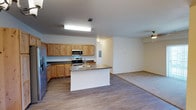 This single-story residence is designed with an open-concept layout that integrates the kitchen and living areas into a cohesive, functional space. The kitchen is well-appointed with knotty alder cabinetry offering generous upper and lower storage, dark laminate countertops, stainless steel appliances including a refrigerator, range, and microwave, and a central island with a double sink. Wood-look plank flooring runs throughout the kitchen and transitional areas, lending a warm, consistent aesthetic.

The living area extends naturally from the kitchen and features plush carpeting, a ceiling fan, and wide sliding glass doors fitted with vertical blinds that allow ample natural light. A built-in desk nook provides a practical workspace just off the main living space.

The bedrooms are carpeted and well-sized, each featuring wide windows with horizontal blinds that offer views of the surrounding neighborhood. The rooms are bright and versatile in their layout potential.

Two bathrooms serve the unit, both featuring wood-toned vanity cabinetry, granite-style countertops, and hard surface flooring. One bathroom includes a walk-in shower, while the other features a shower-tub combination. An electrical panel and ceiling fans throughout contribute to the unit's practical, move-in-ready design.