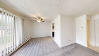 Located at 1800 Rhodes Rd in Kent, Ohio, this two-bedroom, one-bathroom apartment offers a practical and comfortable single-floor layout. The living area is carpeted and well-lit, featuring a ceiling fan, a wall-mounted air conditioning unit, and a sliding glass door dressed with vertical blinds that fills the room with natural light and provides a view of the surrounding greenery. Baseboard heating runs throughout, ensuring year-round comfort. The kitchen is positioned adjacent to the living area and is equipped with dark espresso cabinetry, granite-style countertops, a stainless steel sink, and tile flooring, offering a clean, updated aesthetic. The generously sized primary bedroom features plush carpeting, natural light from a window with blinds, and a mirrored sliding-door closet for ample storage. The second bedroom is similarly carpeted with natural light and baseboard heating. An entryway with a closet provides convenient storage upon entry. The bathroom is well-appointed with tile flooring, a wood-look tiled tub and shower surround, and warm wood-toned cabinetry with a white countertop. The textured ceilings throughout contribute to the cohesive, low-maintenance character of the space.