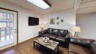 Located at 1306 N Lincoln Ave in Urbana, Illinois, this single-floor residence offers a functional and practical layout across several well-defined living spaces. The living room features rich hardwood-style flooring, a wall-mounted flat-screen TV, a skylight overhead panel for added brightness, and a textured ceiling, creating a comfortable and casual gathering space. Adjacent to the living area, the kitchen is outfitted with white cabinetry, tile backsplash, laminate countertops, and a full suite of white appliances including a dishwasher, microwave, and range. A window above the sink allows natural light to fill the space, and hardwood-style flooring continues throughout. The residence includes multiple carpeted bedrooms, each equipped with a ceiling fan, a window with blinds, and a closet with built-in shelving rods for storage. The bathroom features tile flooring, a single-basin vanity with a large wall mirror, open wood shelving above the toilet, and a private walk-in shower stall with a curtain. The overall design is clean and straightforward, offering comfortable, practical living in a well-organized single-level floor plan.