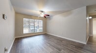This single-floor residence offers a thoughtfully laid out interior with a blend of practical finishes and comfortable living spaces. The main living area is bright and open, featuring durable wood-look flooring, neutral-toned walls, a textured ceiling, and a ceiling fan with integrated lighting. A wide window fitted with blinds allows generous natural light to fill the room while providing views of the surrounding greenery.

Adjacent to the living area, a dining space connects seamlessly to the kitchen, which is equipped with dark cabinetry, granite-style countertops, a double sink, and a full suite of black appliances including a range, microwave, dishwasher, and refrigerator. Wood-look flooring continues throughout this zone, and a built-in shelving unit near the entryway provides convenient storage and display space.

The bedrooms are finished with plush carpeting and feature windows with blinds that bring in soft, diffused natural light. One bedroom includes a ceiling fan, adding to the comfort of the space.

Throughout the residence, clean white baseboards, neutral paint tones, and consistent finishes create a cohesive and move-in ready aesthetic. The floor plan, as revealed by the 3D model, offers a well-organized layout with clearly defined living, dining, kitchen, and sleeping areas.