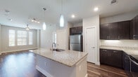 This contemporary single-floor residence showcases a thoughtfully designed open-concept layout that seamlessly connects the kitchen and living areas. The kitchen is a standout feature, equipped with dark espresso cabinetry, granite countertops, a large central island with an undermount sink, and a full suite of stainless steel appliances including a refrigerator, electric range, built-in microwave, and dishwasher. Elegant pendant lighting illuminates the island, while recessed lighting and track lighting enhance the overall brightness of the space.

Rich hardwood-style flooring runs throughout the main living areas and kitchen, adding warmth and visual continuity. The bedrooms offer a comfortable retreat, with plush carpeting, ceiling fans with integrated lighting, and multiple windows dressed with white horizontal blinds that invite generous natural light and outdoor views.

The bathrooms are finished to a high standard. The primary bathroom features a navy blue vanity with granite countertops, a framed mirror, and a glass-enclosed walk-in shower, while the secondary bathroom includes large-format wall tile surrounding a soaking tub and shower combination. Both bathrooms continue the hardwood-style flooring seen throughout the home, creating a cohesive and polished aesthetic from room to room.