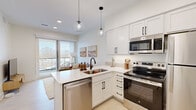 Located at 220 Quimby St NE in Grand Rapids, Michigan, this efficiently designed one-bedroom, one-bathroom unit offers a thoughtful open-concept layout that maximizes every square foot. The contemporary kitchen is a standout feature, showcasing white shaker-style cabinetry with matte black hardware, light quartz countertops, a stainless steel appliance suite including a range, over-the-range microwave, refrigerator, and dishwasher, and a peninsula with an undermount sink. Globe pendant lights add a modern touch overhead, while the open sightline to the living area enhances the sense of space. Light-toned luxury vinyl plank flooring runs throughout, contributing to the clean, bright aesthetic. The bedroom is a well-proportioned retreat featuring a large picture window that invites abundant natural light and offers views of the surrounding neighborhood. Additional windows along the bedroom walls further amplify the airy feel of the space. The bathroom is finished with white cabinetry, a single-basin vanity, and a walk-in shower with a curtain rod, all accented with matte black fixtures that complement the home's cohesive modern design. Clean white walls and recessed lighting throughout the unit create a crisp, contemporary ambiance well-suited to urban living in Grand Rapids.