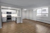 This well-appointed two-bedroom, one-bathroom unit at 20 Elizabeth Street North in Mississauga offers a thoughtfully designed layout across a single floor. Light-toned hardwood-style flooring runs throughout, complementing the bright, neutral palette that defines the space.

The kitchen is a standout feature, showcasing white shaker-style cabinetry extending to the ceiling, a clean white quartz countertop, and a full suite of stainless steel appliances including a refrigerator, electric range, built-in microwave, and dishwasher. A peninsula with a double undermount sink opens directly to the living area, creating a functional and connected open-concept layout. The living room benefits from large windows that allow natural light to fill the space, and is equipped with a wall-mounted ductless air conditioning unit alongside baseboard heating.

The primary bedroom is a comfortable size, featuring a wall-mounted AC unit, a closet, and a window. The second bedroom is bright and open with its own window. The full bathroom includes a soaker tub and shower combination, a white vanity with storage, and a lighted mirror. In-unit laundry is also present, as seen in the floor plan.