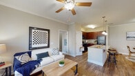 Located at 1300 S Park Way in Sanford, NC, this single-floor residence offers a thoughtfully designed open-concept layout that seamlessly connects the living, dining, and kitchen areas. The living room features warm hardwood-style flooring, crown molding, a ceiling fan, and large windows dressed with plantation shutters and drape panels that invite abundant natural light. The kitchen is outfitted with rich dark cherry cabinetry, granite countertops, a functional center island with a sink, and black appliances including a refrigerator, range, and built-in microwave. The adjacent dining area provides an intimate setting with easy access to the kitchen. Multiple bedrooms are finished with plush carpeting, ceiling fans, and windows that bring in natural light, with each room offering dedicated closet space. The primary bedroom is generously sized with comfortable proportions. Two full bathrooms are finished with tile flooring, granite-topped dark wood vanities, and tub-shower combinations with curved curtain rods. Neutral warm-toned walls run throughout the entire residence, creating a cohesive and welcoming ambiance. The overall design balances practicality with comfort, making this a well-rounded and functional living space.