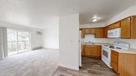 Located at 3451 Grand Ave in Des Moines, Iowa, this single-floor unit offers a practical and well-organized layout throughout. The kitchen is appointed with warm oak cabinetry — both upper and lower — along with white appliances including a refrigerator, electric range, and over-the-range microwave. A double-basin sink and ample counter space provide a functional workspace, all set atop durable wood-look plank flooring. The kitchen opens toward the living area, which transitions to plush carpeting and features a wall-mounted air conditioning unit and baseboard heating for year-round comfort. A standout feature of the living space is a sliding glass door that leads to a private balcony, offering pleasant views of the surrounding neighborhood and greenery. The bedrooms are carpeted and well-lit, each equipped with ceiling fans, windows that invite natural light, and baseboard heating. The bathroom includes a full tub and shower combination with clean white surrounds and a wooden vanity. Throughout, the unit maintains a clean, neutral palette with white walls and textured ceilings, creating a bright and welcoming atmosphere well-suited for comfortable everyday living.