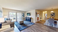 Located at 3901 Noyes Circle in Randallstown, Maryland, this well-appointed single-floor residence offers two bedrooms and two full bathrooms across a thoughtfully designed layout. Light-toned walls and wood-look plank flooring run throughout the home, creating a cohesive and welcoming atmosphere.

The living room provides generous space for relaxing and entertaining, featuring a large sliding glass door that fills the room with natural light and opens to an outdoor area. Adjacent to the living room is a dedicated dining area highlighted by a bright window with blue curtain panels and a pendant light overhead.

The galley-style kitchen is lined with warm honey-toned wood cabinetry, gray countertops, and white appliances, including a range and dishwasher. It opens directly into the dining space, making the layout ideal for everyday living.

The primary bedroom is a comfortable retreat, offering a walk-in closet and warm, neutral tones. The second bedroom features a large double-door closet and a window with outdoor views. Both bathrooms include wood-tone vanities with white countertops — one with a step-in shower and the other with a full tub-shower combination. The overall design is clean, bright, and functional throughout.