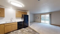 Located at 540 McKinley Ave in Clintonville, Wisconsin, this single-floor, 2-bedroom, 1-bathroom unit offers a practical and comfortable layout throughout. The combined kitchen and living area forms the heart of the home, with the kitchen featuring warm oak cabinetry, black appliances including a refrigerator, dishwasher, and electric range with built-in microwave, and wood-look luxury vinyl flooring. The living room is generously sized and bathed in natural light, with plush carpet underfoot and a large sliding glass door that opens to an outdoor patio area with views of surrounding greenery. A wall-mounted AC unit provides additional climate control alongside baseboard heating found throughout the unit. Both bedrooms are well-proportioned, carpeted, and equipped with ceiling fans and natural light from windows. The primary bedroom features a walk-in closet with built-in shelving and hanging rods, offering ample storage. A second closet provides additional organization space. The full bathroom showcases wood-look tile flooring, oak vanity cabinetry, a soaking tub with grab bar, and a clean, neutral finish. Warm wood trim accents and a consistent neutral color palette tie the space together, creating a cohesive and move-in-ready living environment.