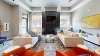 Located in Grand Junction, Colorado, this well-appointed clubhouse and fitness facility offers a comprehensive community amenity space spread across a single level. The layout is thoughtfully divided into distinct functional areas that flow seamlessly from one to the next.

The clubhouse lounge serves as a welcoming social hub, anchored by a striking floor-to-ceiling black tile fireplace wall with a mounted TV. Comfortable neutral sofas and bold orange accent chairs surround the space, while pendant lighting and large windows fill the room with natural light and views of the surrounding community.

Adjacent to the lounge is a full-service kitchen, outfitted with sleek white cabinetry, dark granite countertops, a patterned tile backsplash, stainless steel appliances, and a large island with bar seating — ideal for gatherings and events.

A private office with a vibrant orange accent wall and interior window offers a functional workspace for leasing or management staff.

The expansive fitness center features wood-look flooring, linear LED lighting, floor-to-ceiling mirrors, and a full array of cardio and strength equipment including treadmills, ellipticals, rowing machines, and free weights. A separate fitness studio provides an open, carpeted space with mirrored walls, a Reflect interactive fitness mirror, and ample room for yoga, stretching, or group classes. The welcoming entryway corridor completes the space with curated artwork and stylish seating.