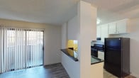 Located at 924 Encinitas Blvd in Encinitas, this single-floor unit offers a well-organized layout with a thoughtful mix of flooring and functional spaces throughout. The living area features smooth hard flooring and a ceiling fan, creating a bright, open atmosphere. A sliding glass door with vertical blinds fills the room with natural light and provides access to the outdoors. The kitchen is efficiently designed in a galley configuration, outfitted with white cabinetry, dark granite-style countertops, black appliances including a gas range and full-size refrigerator, and a window that brings in additional natural light. A half-wall pass-through connects the kitchen to the main living area, adding an open, communicative feel between the two spaces. The bedroom features plush carpeting, a ceiling fan with a light fixture, a window for natural light, and convenient access to a walk-in closet. The bathroom is clean and straightforward, complete with a full tub-shower combination with tiled surround and chrome fixtures. Textured ceilings are present throughout the unit, adding a classic residential character to each room.