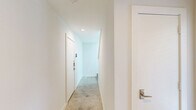 Located at 1510 N Carroll Ave in Dallas, TX, this contemporary multi-story home offers a well-designed layout across three floors. The entry level features a hallway with clean white walls, recessed lighting, and neutral-toned flooring, setting a bright, modern tone throughout. Staircases with dark-stained treads and white risers connect the floors with understated elegance.

The main living level hosts an open-concept kitchen and living room. The kitchen is well-appointed with white shaker cabinets, light quartz countertops, stainless steel appliances including a gas range and French door refrigerator, and a large undermount sink on the central island. Light wood-tone flooring extends throughout this level, complemented by recessed lighting that keeps the space bright and airy.

The upper floor contains the bedrooms, each carpeted and bathed in natural light through large windows with views of the surrounding Dallas neighborhood. The primary bedroom features impressively high ceilings and direct access to an en-suite bathroom, offering a private retreat. The four bathrooms across the home include tile flooring, white vanities, and at least one full bath with dark tile surround and a tub-shower combination. Two closets and a hallway complete the functional layout of this thoughtfully designed Dallas home.