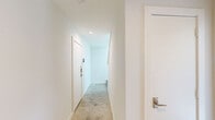 Located at 1510 N Carroll Ave in Dallas, TX, this contemporary multi-story home offers a well-designed layout across three floors. The entry level features a hallway with clean white walls, recessed lighting, and neutral-toned flooring, setting a bright, modern tone throughout. Staircases with dark-stained treads and white risers connect the floors with understated elegance.

The main living level hosts an open-concept kitchen and living room. The kitchen is well-appointed with white shaker cabinets, light quartz countertops, stainless steel appliances including a gas range and French door refrigerator, and a large undermount sink on the central island. Light wood-tone flooring extends throughout this level, complemented by recessed lighting that keeps the space bright and airy.

The upper floor contains the bedrooms, each carpeted and bathed in natural light through large windows with views of the surrounding Dallas neighborhood. The primary bedroom features impressively high ceilings and direct access to an en-suite bathroom, offering a private retreat. The four bathrooms across the home include tile flooring, white vanities, and at least one full bath with dark tile surround and a tub-shower combination. Two closets and a hallway complete the functional layout of this thoughtfully designed Dallas home.