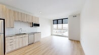 Located at 500 W 41st Ave in Denver, Colorado, this modern unit offers a thoughtfully designed single-floor layout with clean lines and contemporary finishes throughout. Light wood-tone luxury vinyl flooring runs continuously across the entire space, contributing to a bright, cohesive aesthetic.

The open-concept living and kitchen area serves as the heart of the unit. The kitchen is outfitted with light wood cabinetry, stainless steel appliances including a refrigerator, dishwasher, and microwave, a stainless steel sink with a modern faucet, and a white subway tile backsplash. Generous counter space complements the efficient, well-organized layout.

Large floor-to-ceiling windows flood the living area with natural light and frame sweeping elevated views of the surrounding Denver cityscape and neighborhood rooftops — a standout feature of the space. Black roller shades provide adjustable light control.

The bedroom is a quiet, private space with a sliding-door closet offering built-in shelving and hanging storage. An additional compact room provides flexible use as an office or den, with crisp white walls and continued wood flooring.

The bathroom features a glass-enclosed walk-in shower with white tile surround, a light wood vanity with a taupe countertop, an undermount sink, and a large mirror. The overall ambiance is clean, minimal, and move-in ready.